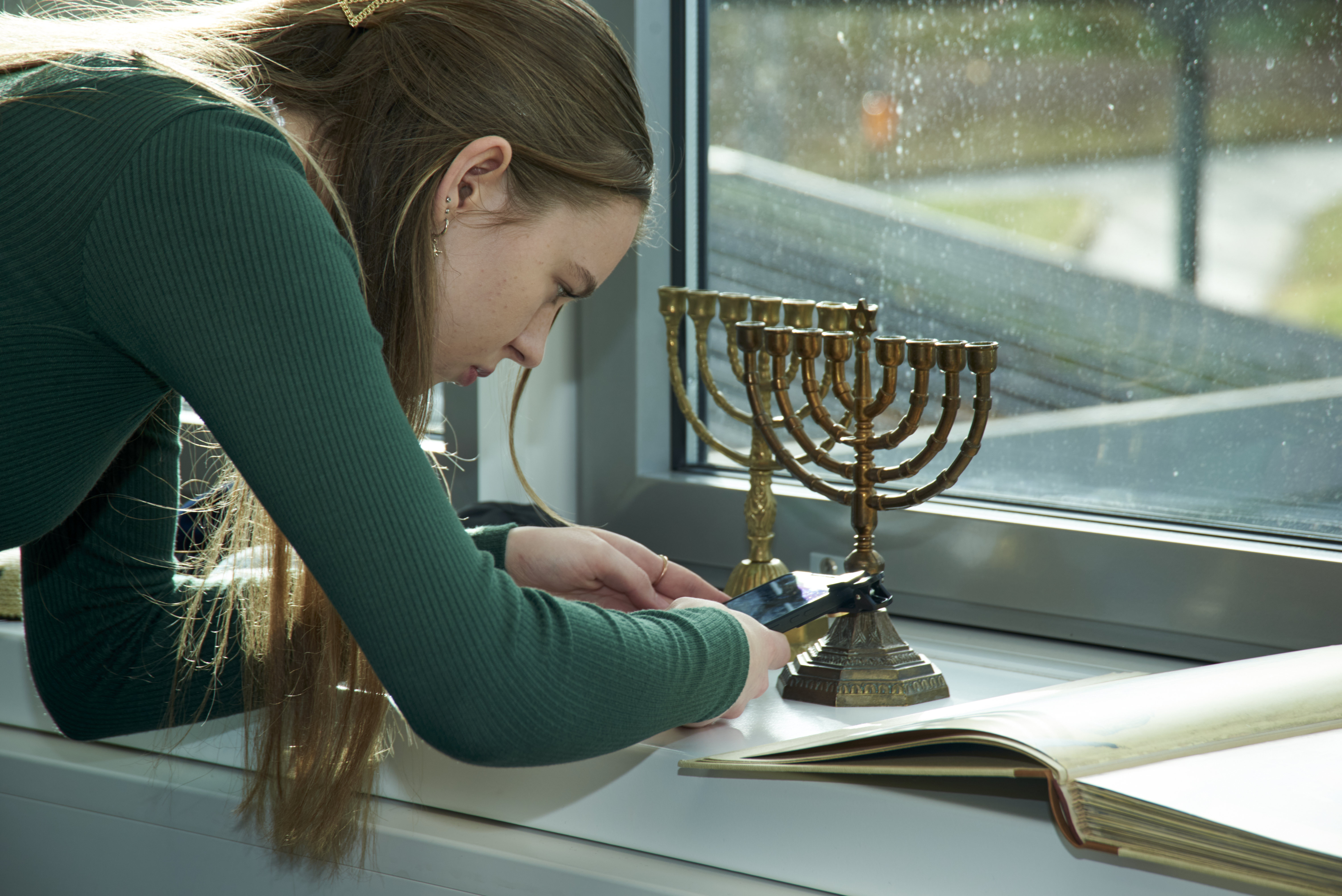 Schülerin fotografiert Menora mit ihrem Smartphone