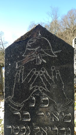 Der Grabstein von Moritz Strauss mit Pickelhaube, Gewehr und jüdischer Segensgeste verziert